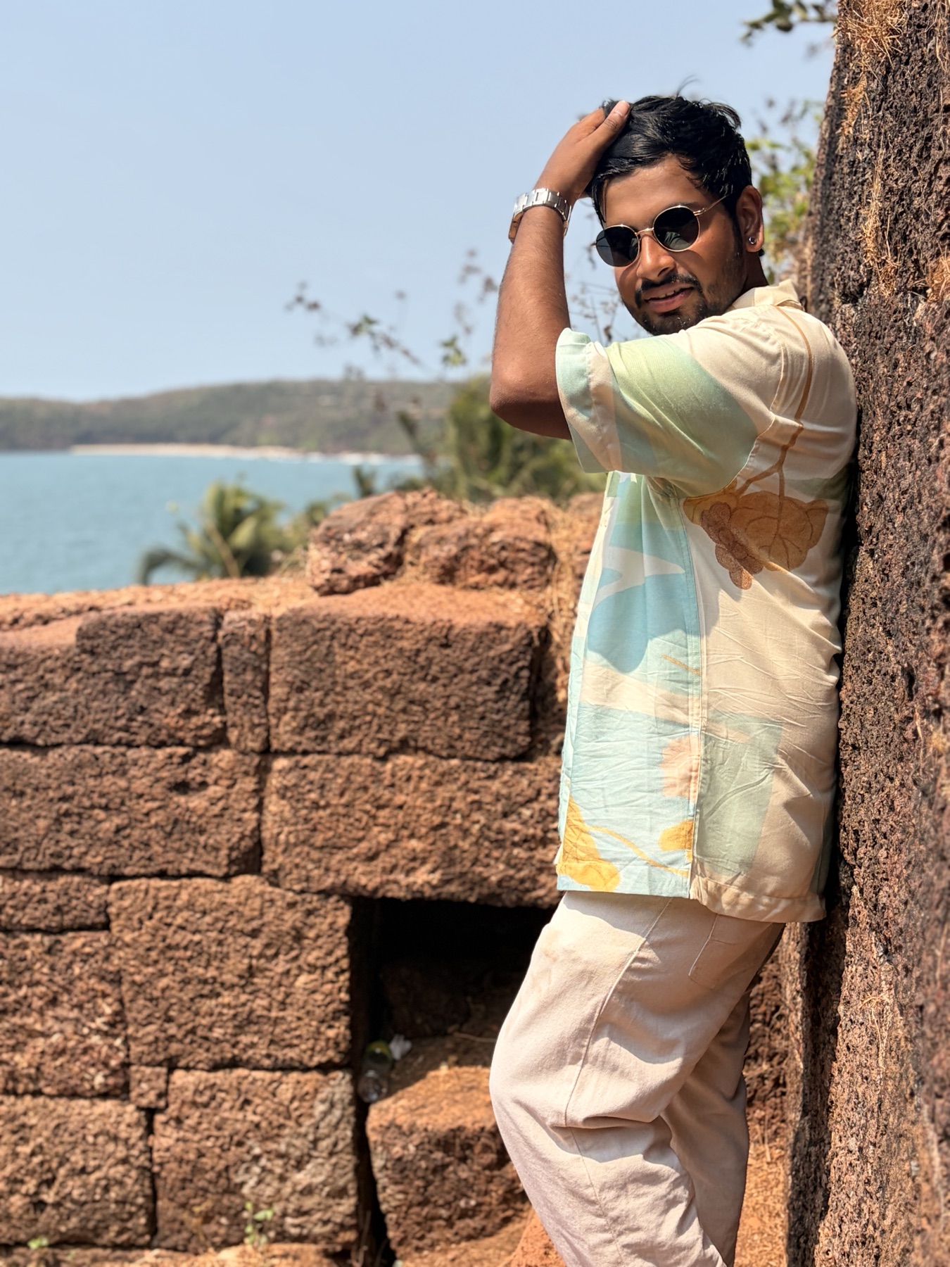 Ankit in sunglasses beside an old coastal fort wall