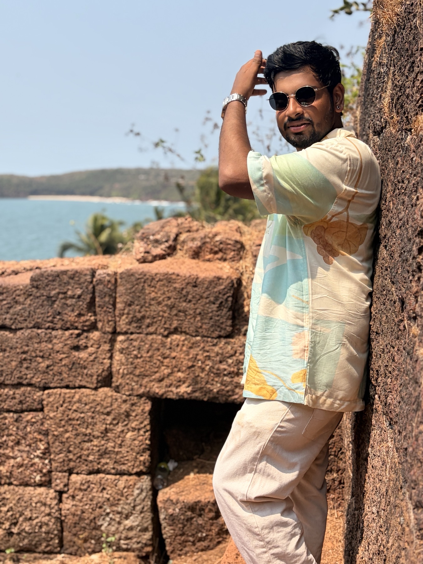 Ankit leaning against an old fort wall near the sea