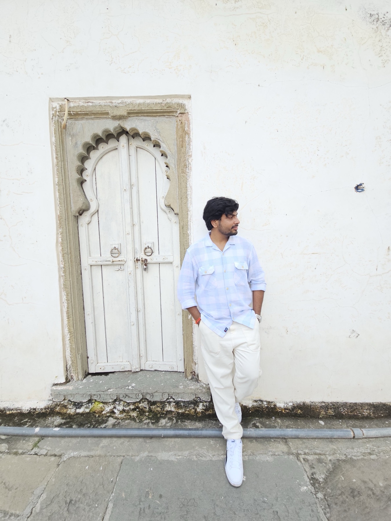 Ankit in a pale blue shirt beside a carved heritage doorway