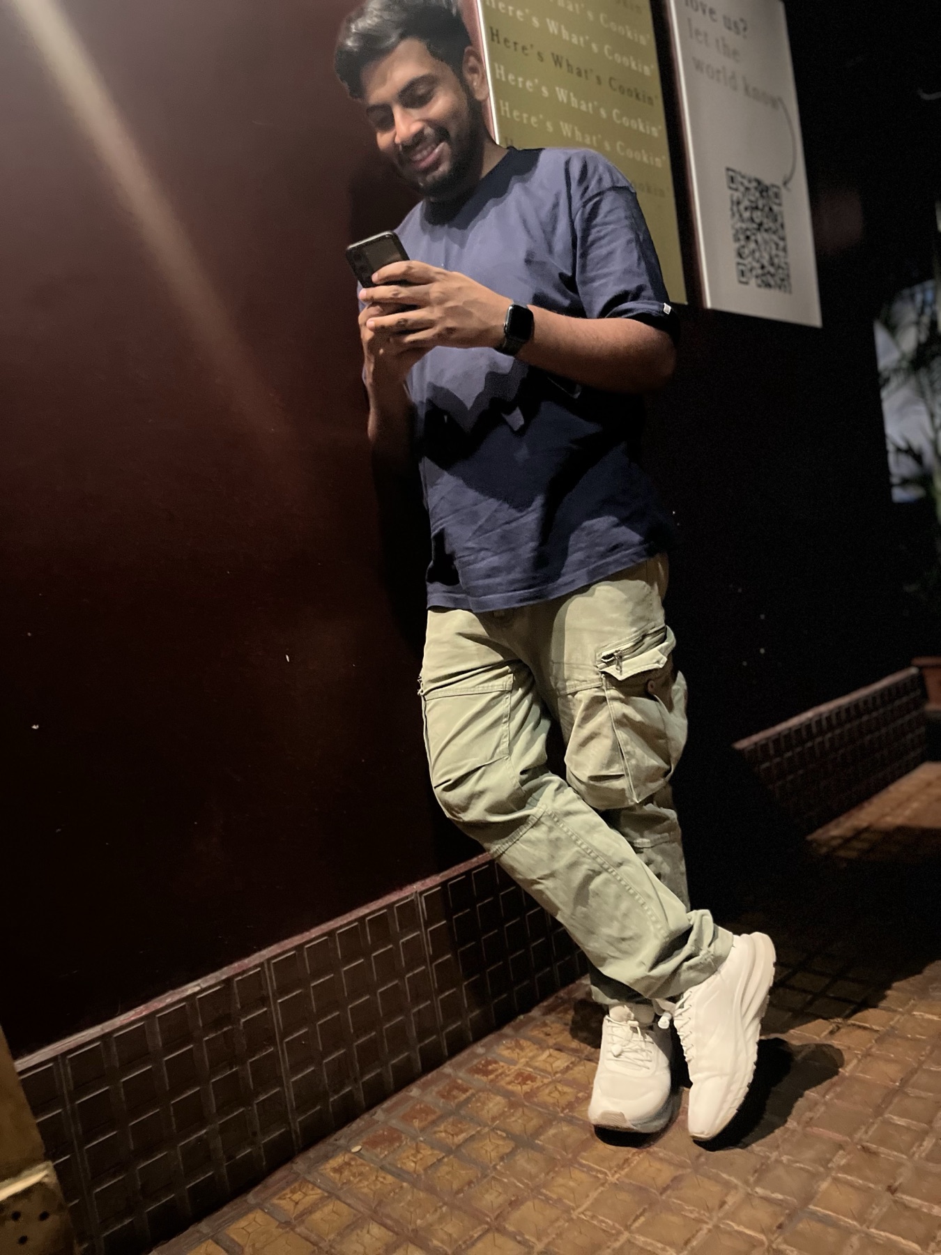 Ankit smiling at his phone during a relaxed evening