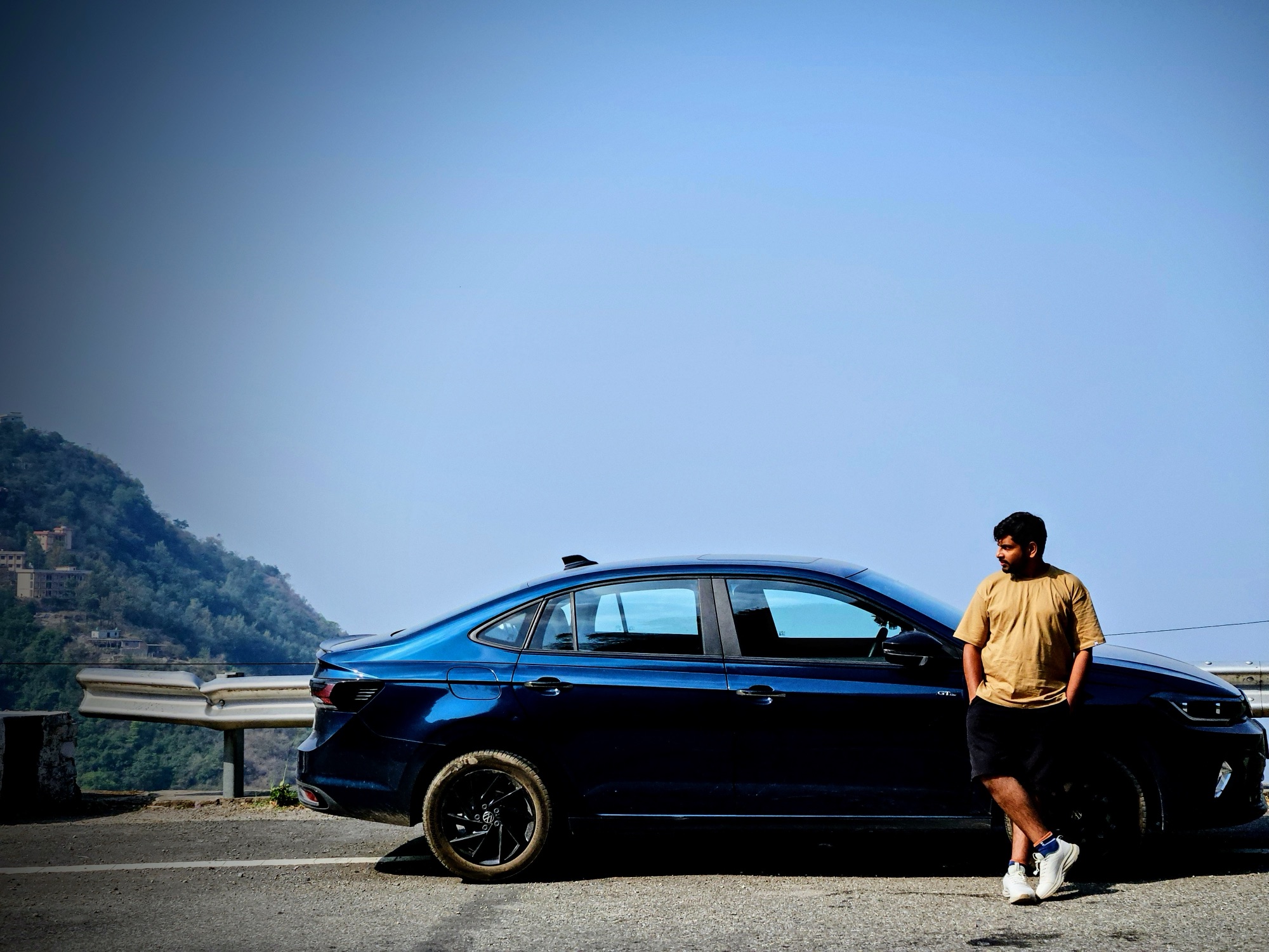 Ankit standing beside his blue Volkswagen Virtus, Sapphire