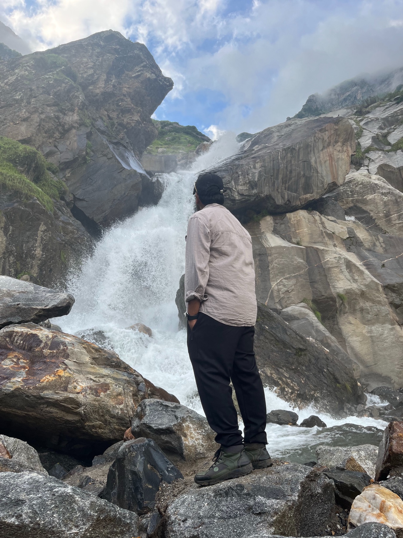 Ankit standing before a powerful mountain waterfall
